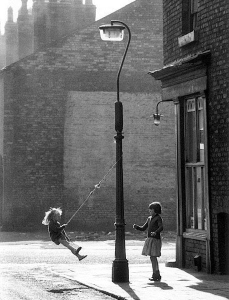 Girls swinging on a lamppost. Foto: Shirley Baker. Licencia CC 